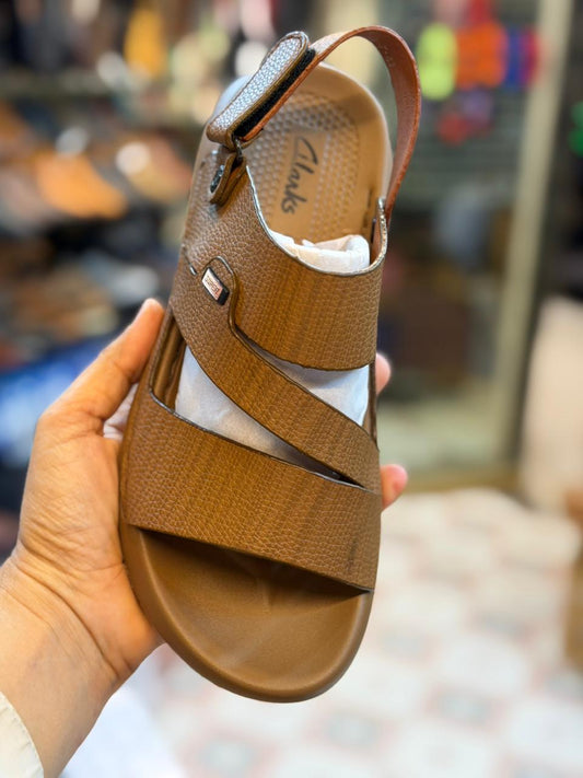 Brown sandal held in a hand with a blurred background