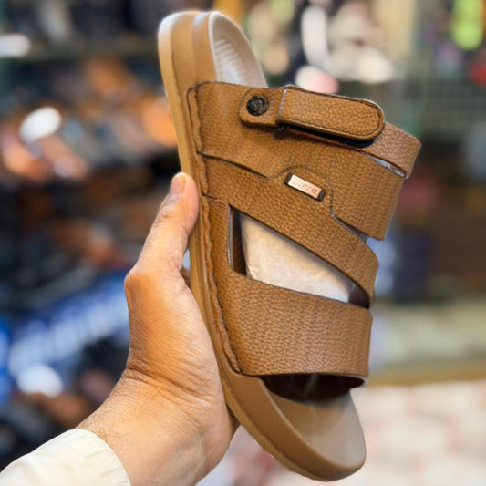 Brown sandal held in a hand with a blurred indoor background