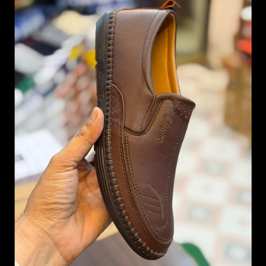Brown leather shoe held by a hand with a blurred store background